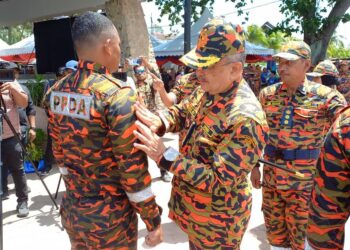 MOHD. ALI Mohd. Rustam memakaikan lambang kepada salah seorang anggota bomba sempena Majlis Penutup  Kursus Pengurusan Bencana di Pentas Budaya, Pantai Puteri, Melaka. - UTUSAN/AMRAN MULUP