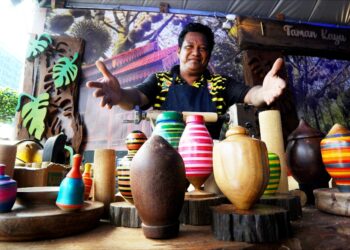MOHD. YUNUS ISMAIL menunjukkan pelbagai jenis gasing yang dijual di gerai Segamat sempena Festival Majestic Johor 2022 di Puteri Harbour Iskandar Puteri.