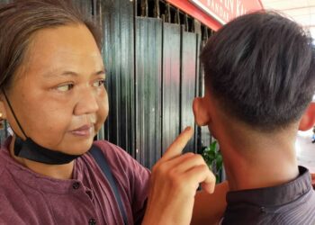 NORWANI Abdul Wahid menunjukkan bahagian telinga anaknya yang dipukul rakan sebaya dalam kejadian di sebuah sekolah menengah di Kuala Kangsar, Isnin lalu. - UTUSAN