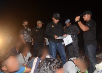 KHAIRUL Dzaimee Daud (berdiri tengah) bersama sebahagian daripada pekerja asing yang ditahan untuk diperiksa dalam satu serbuan oleh Jabatan Imigresen  di Tasek Gelugor, Pulau Pinang malam tadi. - UTUSAN/IQBAL HAMDAN