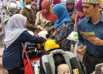 IBU bapa melihat pameran sempena Program Inisiatif Keselamatan Pejalan Kaki dalam Kalangan Kanak-Kanak Sekolah di Kadok, Kota Bharu, Kelantan. - UTUSAN/ROSALWANI CHE SOH