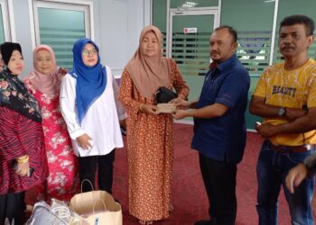 PENGHULU, Mohd. Yusof Botak (dua dari kanan) menyampaikan sumbang wang tunai mewakili Pejabat Daerah dan Tanah Melaka Tengah kepada Robiah Saidin sambil diperhatikan Tuminah Kadi di Japerun Pantai Kundor, Melaka. - UTUSAN/AMRAN MULUP