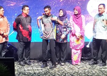 NORAINI Ahmad memakaikan jaket kepada salah seorang pelajar sambil diperhatikan Ketua Menteri Melaka, Datuk Seri Sulaiman Md. Ali selepas pelancaran Briged Sukarelawan IPT #KPTPrihatin di sebuah hotel di Ayer Keroh, Melaka. - UTUSAN/AMRAN MULUP