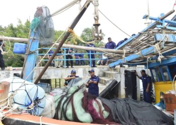 WAN MUHAMMAD AZNAN Abdullah (bawah, kiri) melakukan pemeriksaan ke atas bot nelayan Vietnam di jeti Pengkalan Perlindungan Sumber Kuantan, di Padang Lalang di Kuantan, Pahang - UTUSAN/SHAIKH AHMAD RAZIF