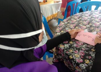 YATI merenung catatan hatinya yang diberikan kepada tiga anaknya yang datang ke Majlis Jalinan Kasih di Penjara Simpang Renggam, Kluang.
