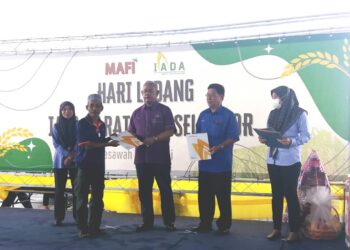NOH Omar menyerahkan sijil penghargaan kepada pesawah di Tanjong Karang hari ini.
