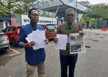 DR. Ismail Salleh (kanan) dan Mohd. Asmirul Anuar Aris memegang salinan laporan polis dan akhbar Utusan Malaysia selepas membuat laporan di IPD Kota Setar, Alor Setar di sini. -UTUSAN/MOHD RIFAAT ABD HAMID