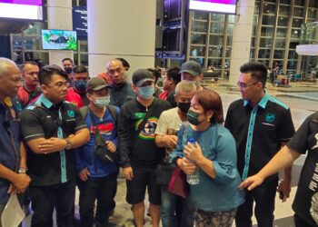 MUSA Hassan (kiri) dan Hishamuddin Hashim (dua dari kiri) bersama lima mangsa (bertopi hitam) dan ahli keluarga mangsa di balai ketibaan di Lapangan Terbang Antarabangsa Kuala Lumpur (KLIA). - UTUSAN/PETAH WAZZAN ISKANDAR