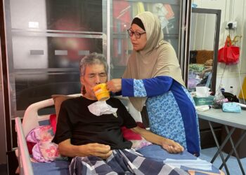 ZAINUN Majid memberikan minuman kepada Roslan Saleh di kediaman mereka di Jalan Rantau Panjang, Alor Gajah, Melaka.