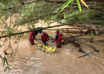 ANGGOTA bomba mengambil mayat yang tersangkut pada dahan pokok di dalam sungai di Kampung Air Panas, Gerik hari ini. - UTUSAN