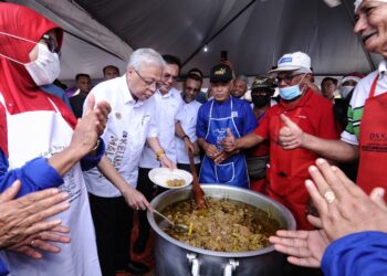 ISMAIL Sabri Yaakob tidak melepaskan peluang mencuba menggaul lauk Masak Lempap yang dihasilkan penduduk kampung ketika beliau menghadiri Program Kenduri Sekampung Keluarga Malaysia @ Jempol di padang Sekolah Menengah Kebangsaan Felda Palong 7, Palong di Jempol hari ini. - UTUSAN/MOHD. SHAHJEHAN MAAMIN