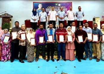 AZLAN Man (belakang, tiga dari kiri) bergambar  bersama para penerima sewaktu Majlis Penyerahan Dokumen Hak Milik Tanah Kerajaan di Negeri Perlis di Dewan Besar Felda Chuping, Padang Besar, Perlis, hari ini. -UTUSAN/ASYRAF MUHAMMAD