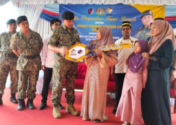 ZAMBERY Jeffery Darus (tiga kiri) menyerahkan replika kunci kepada Mazna sempena majlis penyerahan kunci rumah inisiatif perumahan veteran ATM di Kampung Baru Nelayan, Tumpat, Kelantan.-UTUSAN/ROHANA ISMAIL