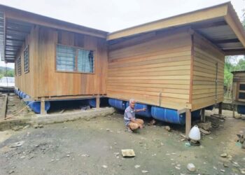 A. BAKAR Che Ahmad menunjukkan tong yang digunakan untuk membina rumah terapung di Kampung Tebak, Air Putih, Kemaman, Terengganu, semalam.