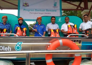 M. ZAKI Mahat (dua dari kanan) dan Kamarulsyah Muslim (tiga dari kiri) bersama pelbagai peralatan logistik yang disumbangkan Petronas untuk bantuan banjir di Padang Kawad APM, Ayer Keroh, Melaka. - UTUSAN/AMRAN MULUP