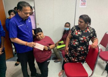 S A Vigneswaran (kiri) menyampaikan bantuan perubatan berjumlah RM15,000 kepada K Chitra bagi tujuan pembedahan akibat ketumbuhan dalam perut di Sungai Siput hari ini. - UTUSAN