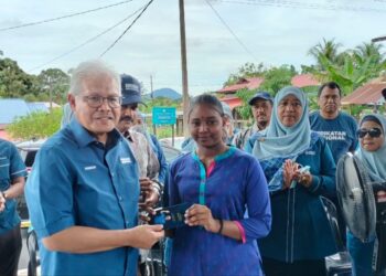 HAMZAH Zainudin (kiri) menyampaikan bantuan Deepavali kepada penduduk di Dewan Terbuka Kampung Ulu Sepetang di Larut  hari ini. - UTUSAN/WAT KAMAL ABAS