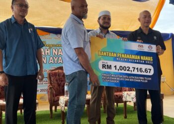 DR. Nik Muhammad Zawawi Salleh (dua dari kiri) ketika menyampaikan replika cek bantuan kepada wakil penanam nanas di Pasir Puteh, Kelantan hari ini. UTUSAN/TOREK SULONG