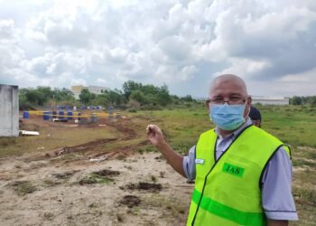 ROSLI Zul menunjukkan longgokan tong berisi cecair bahan buangan terjadual yang ditemukan di kawasan lapang di Kampung Kepayang, Simpang Pulai di Ipoh hari ini. - UTUSAN