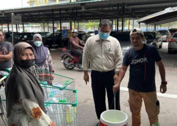 MAS Imran Adam (kanan) membantu seorang wanita mengisi air ke dalam botol di Pasaraya Econsave Permas Jaya.