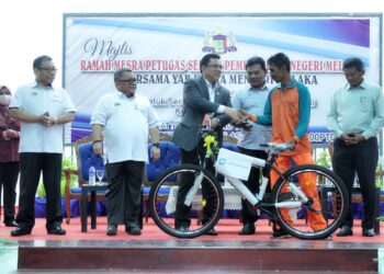 SULAIMAN Md. Ali menyerahkan sebuah basikal kepada seorang pekerja pembersihan pada Majlis Ramah Mesra Pekerja Sektor Pembersihan di Dewan Hang Tuah, Melaka. - UTUSAN/RASUL AZLI SAMAD