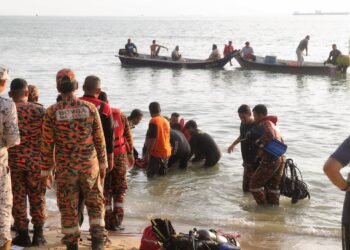 ANGGOTA bomba dan penyelamat serta orang awam mengangkat mayat mangsa yang lemas di Pantai Kundor, Tangga Batu, Melaka. - UTUSAN/RASUL AZLI SAMAD