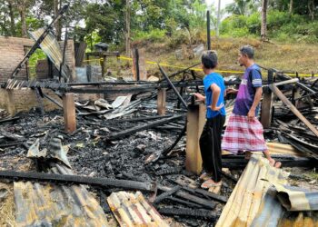 CHE Norihar Che Nawi (kanan) melihat rumah sewa yang didiami di Rancangan Kemajuan Tanah (RKT) Jeram Tekoh, Gua Musang, Kelantan musnah dalam kebakaran. -UTUSAN/AIMUNI TUAN LAH