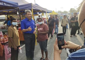 PENGUNJUNG Pasar Malam Chembong, Rembau tidak melepaskan peluang bergambar bersama Mohamad yang juga calon BN di Parlimen Rembau.-UTUSAN/NOR AINNA HAMZAH.