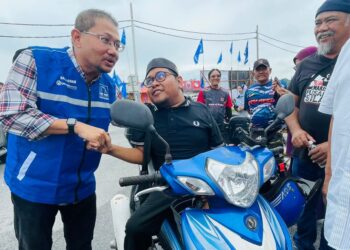 ADNAN Abu Hassan (kiri) bersama seorang penunggang motosikal Orang Kurang Upaya (OKU) pada Program Tukar Minyak Hitam Motosikal di Juasseh, Kuala Pilah hari ini.-UTUSAN/AFIFI HAFIZ MOHD. NOR.