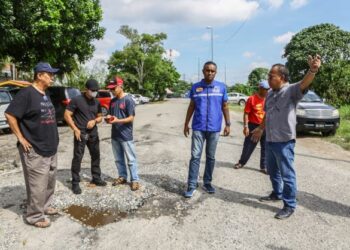 Orang ramai menunjukkan masalah kerosakan jalan raya di hadapan SK Johan Setia kepada Kajendran (dua dari kanan) semalam. – UTUSAN/AFIQ RAZALI.