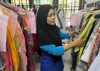 CIK SYAFAWATI Che Radzi menyusun pakaian pelanggan di kedai dobinya di Jalan Tenggiri, Seberang Perai, Pulau Pinang baru-baru ini.