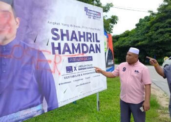 MOHD. GHAZALI Baharuddin (kanan) menunjukkan papan kempen Shahril Sufian Hamdan yang disembur cat merah di persimpangan Kampung Air Pasir, Machap Jaya, Melaka. - UTUSAN/AMRAN MULUP