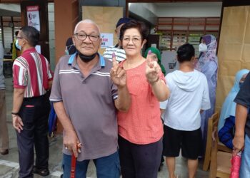ZAHARI Hashim dan Teh See Neo menunjukkan jari selepas mengundi di SK Datuk Demang Hussin, Bukit Katil, Melaka. - UTUSAN/AMRAN MULUP