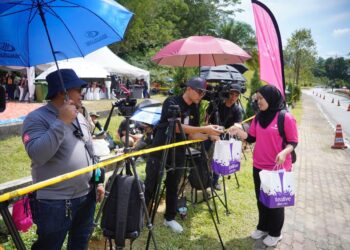WAKIL dari syarikat Tealive menyampaikan pek yang mengandungi minuman jenama itu kepada pengamal media di hadapan Istana Negara, hari ini. -UTUSAN/AMIR KHALID
