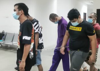 Tertuduh (dua dari kanan) diiringi oleh anggota polis semasa menghadiri perbicaraan di Mahkamah Kota Bharu, Kelantan hari ini.-UTUSAN/ROSALWANI CHE SOH