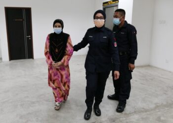 TERTUDUH (kiri) diiringi oleh anggota polis semasa hadir ke Mahkamah Tinggi Kota Bharu, Kelantan. - UTUSAN/ROSALWANI CHE SOH
