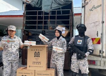 SYED Nor Adli Syed Ab. Rahman (kiri) menunjukkan rokok tidak bercukai yang dirampas dari lori penyeludup di Pejabat Maritim Malaysia Kelantan di Tok Bali, Pasir Puteh, Kelantan hari ini. - UTUSAN/TOREK SULONG