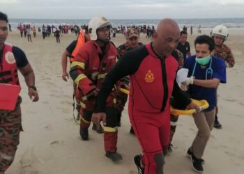 ANGGOTA bomba dan pasukan penyelamat mengusung Akhar Raif Muhamad untuk mendapat rawatan selepas diselamatkan orang awam di Pantai Chendering, Kuala Terengganu, hari ini. - UTUSAN/TENGKU DANISH BAHRI TENGKU YUSOFF