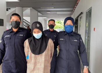 TERTUDUH diiring keluar anggota polis selepas mengaku tidak bersalah di Mahkamah Sesyen, Ayer Keroh, Melaka atas pertuduhan menerima deposit pelaburan. - UTUSAN/MUHAMMAD SHAHIZAM TAZALI