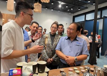 ZAINUDDIN Abdul Wahad mendengar penerangan salah seorang usahawan kopi, Frank Ee selepas perasmian program di Think City, di George Town, Pulau Pinang semalam.