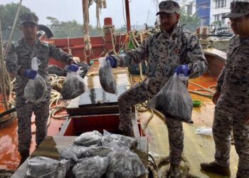 KHAIRULANUAR Abdul Majid menunjukkan sebahagian hasil laut yang dirampas daripada dua buah bot nelayan Vietnam di Kuala Terengganu. - UTUSAN/TENGKU DANISH BAHRI TENGKU YUSOFF
