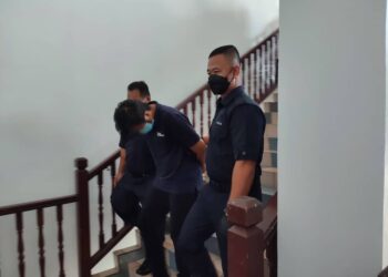 TERTUDUH diiring keluar anggota polis selepas mengaku tidak bersalah di Mahkamah Sesyen, Ayer Keroh, Melaka atas dua pertuduhan melakukan amang seksual fizikal.