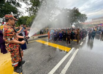 ANGGOTA bomba menyiram air terhadap 100 kanak-kanak yang menyertai Program Berkhatan Perdana Jawi di Nibong Tebal, Pulau Pinang. - UTUSAN/SITI NUR MAS ERAH AMRAN