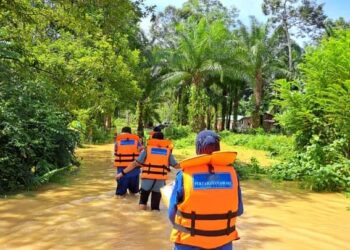 TIGA orang anggota APM meredah kawasan banjir untuk memberikan bantuan di Kampung Lubuk Kulit, Mukim Telang di Lipis, Pahang. - UTUSAN/IHSAN APM LIPIS