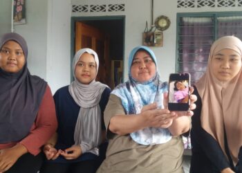 FAIZAH Mat Sam (tengah) menunjukkan gambar Shah Faraz yang cedera dalam insiden itu dekat kediamannya di Kampung Bukit Kuching, Jeram, Kuala Selangor, Selangor. -UTUSAN / ISKANDAR SHAH MOHAMED