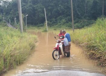 DUA warga emas sedang mencuci motosikal yang terkandas di laluan yang ditenggelami banjir di Kampung Gemuncur di Lipis, Pahang. - UTUSAN/HARIS FADILAH AHMAD