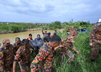 ANGGOTA bomba mengangkat mayat kanak-kanak yang ditemukan terperangkap dalam kereta di Sungai Korok, Jitra di Kubang Pasu. -UTUSAN/MOHD RAFIE AZIMI