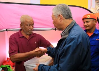 AHMAD Zahid Hamidi (kanan) semasa menyampaikan sumbangan kepada salah seorang mangsa banjir yang ditempatkan di PPS Sekolah Kebangsaan Gual To' Deh, Rantau Panjang, Kelantan.-UTUSAN/KAMARUL BISMI KAMARUZAMAN