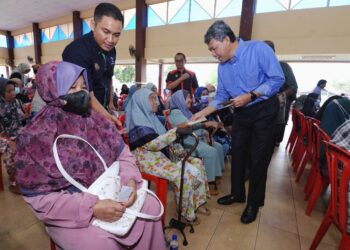 MOHAMAD Hasan menyampaikan sumbangan zakat kepada penerima selepas merasmikan majlis Hari Bertemu Pelanggan, Pertubuhan Peladang Kawasan (PPK) Kawasan Rembau di Rembau hari ini.-UTUSAN/MOHD. SHAHJEHAN MAAMIN.