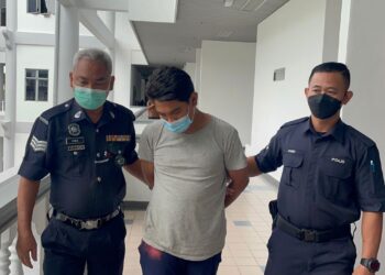 TERTUDUH diiring keluar anggota polis selepas mengaku bersalah di Mahkamah Majistret, Ayer Keroh, Melaka atas pertuduhan melempar bungkusan air kencing dan bekas minyak hitam ke rumah jirannya.